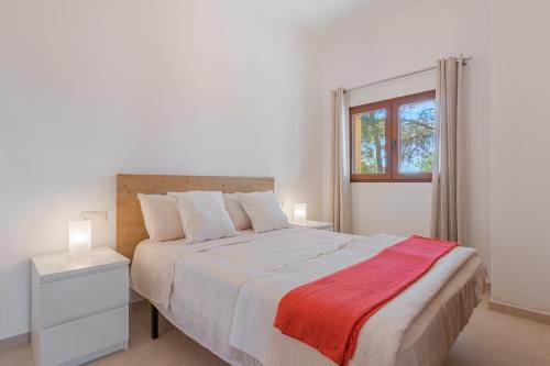 a white bedroom with a large bed and a window at S'escodra in Llucmajor