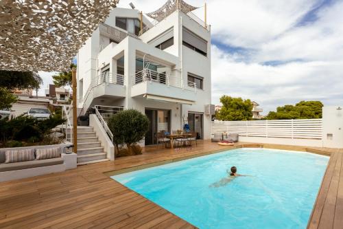 a person swimming in a swimming pool in front of a house at Evaeri villa in Artemida