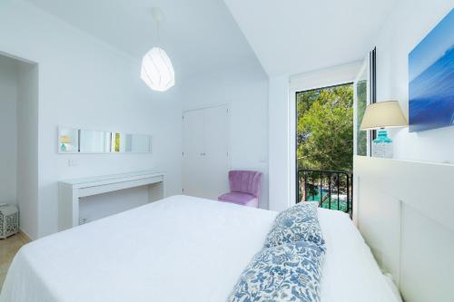 a white bedroom with a bed and a window at Na Pallissera in Santanyi