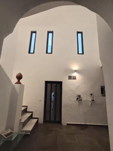 a room with a staircase and a white wall with windows at Casa Privada in Vejer de la Frontera