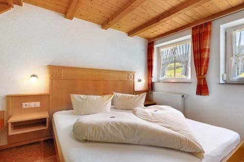 a bedroom with a bed with white sheets and two windows at Danielenhof in Freiamt