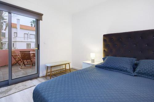 a bedroom with a blue bed and a balcony at Windmill Açores Suite in Furnas