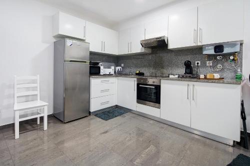 a kitchen with white cabinets and stainless steel appliances at Windmill Açores Suite in Furnas
