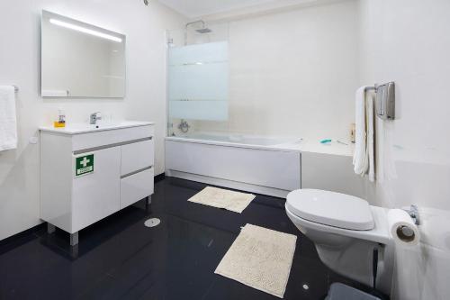 a white bathroom with a toilet and a sink at Windmill Açores Suite in Furnas