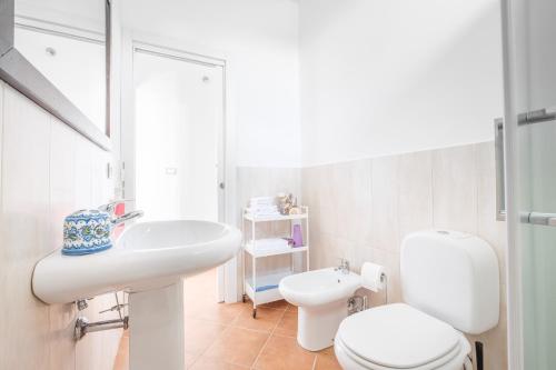 a white bathroom with a toilet and a sink at Medusa Apartment in Taormina