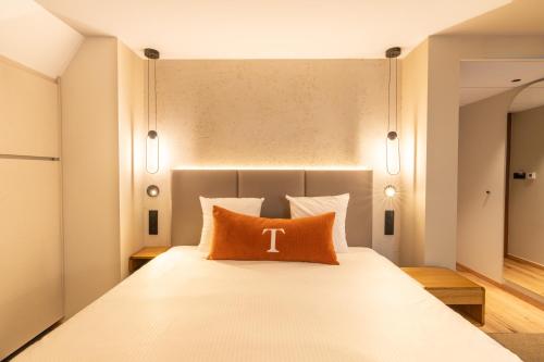 a bedroom with a bed with a pillow with the letter t on it at Hôtel Maison Turenne in Colmar
