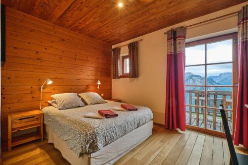 a bedroom with a bed and a large window at Chalet il fera beau demain in Villard-Reculas