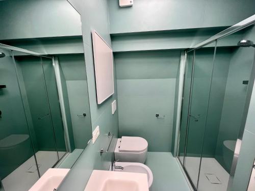 a bathroom with two sinks and a toilet and mirrors at Bruseschi Appartament in Grado