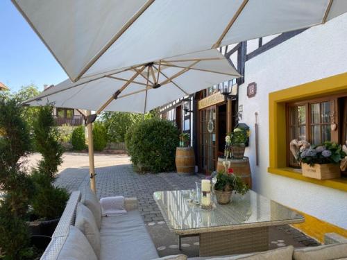 a patio with a table and a white umbrella at Villa Puppenhaus in Immenstaad am Bodensee