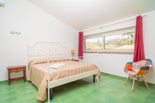 a bedroom with a bed and a chair and a window at Casa Orchidea in Calatabiano