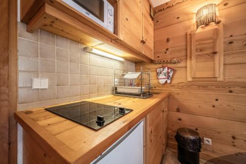 a kitchen with a stove top in a wooden kitchen at Studio Rez-de-jardin, 4 pers Chatel in Châtel