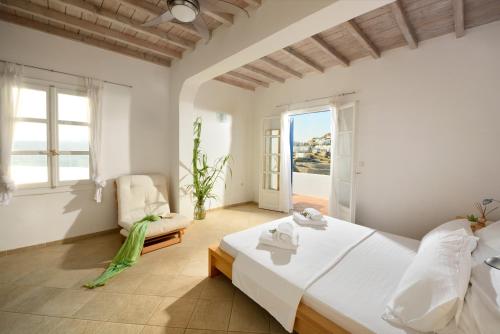 a bedroom with a large white bed and a window at Villa Crysta Mykonos in Mikonos