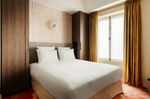 a bedroom with a large white bed and a window at Jills Hôtel in Paris