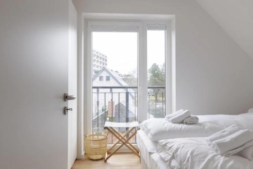 a white bedroom with a balcony with a bed and a window at Strandhafer in Böhl