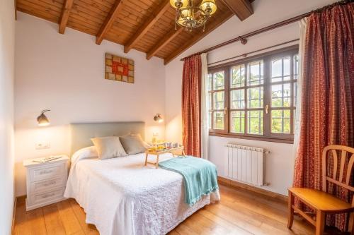 a bedroom with a bed and a chair and a window at Casa Grau in Llanes