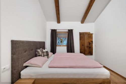 a bedroom with a bed with pink sheets and a window at Herzleierhof Rodeneck in Rodengo