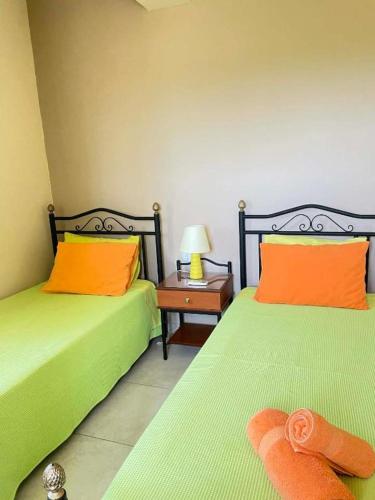 two beds with orange and green sheets in a room at Villas Kavouri in Kryonéri