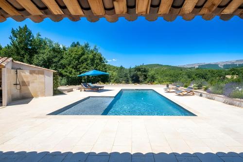 a swimming pool with a table and a blue umbrella at Maison Time-out in Villevieille