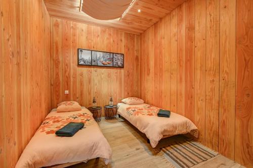 two beds in a room with wooden walls at Maison - Le pic du midi in Roquefeuil