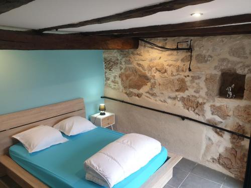a bedroom with a blue bed and a stone wall at Coeur De Causse in Blars