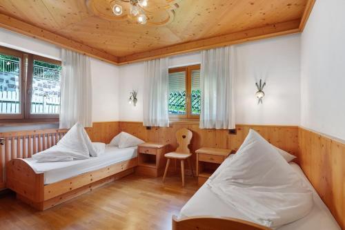 a bedroom with two beds and a desk and a chair at Villa Nussbaumer in Siusi