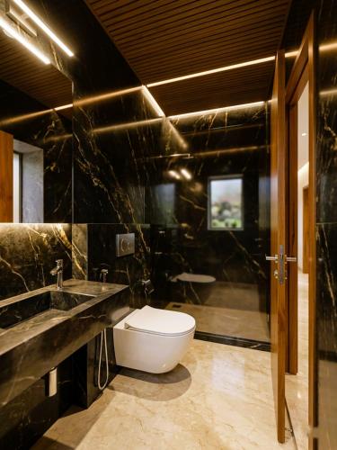 a black bathroom with a toilet and a sink at Hotel National - Grant Road in Mumbai