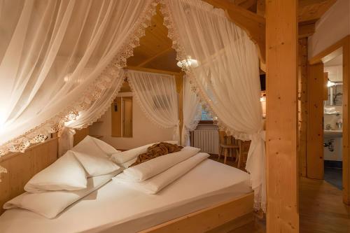 a bedroom with a canopy bed with white curtains at Rossalm in Brixen