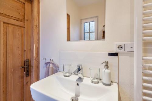 a bathroom sink with two glasses and a mirror at Homertstuebchen in Eslohe