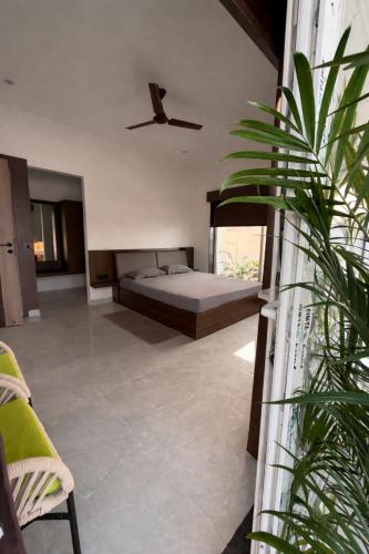 a bedroom with a bed and a plant at Kaashi Flora Whitehouse-9BHK in Varanasi