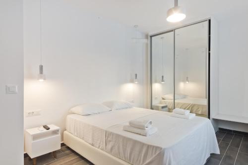 a bedroom with a white bed and a large mirror at Helios Apartment 2 in Karpathos