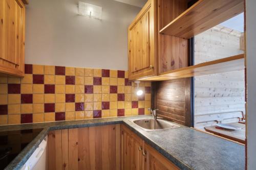 a kitchen with wooden cabinets and a sink at Appartement N° 46 in Les Menuires