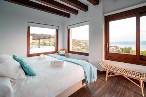 a bedroom with a large bed and two windows at The Cube in Zahara de los Atunes