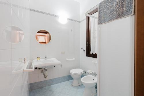 a white bathroom with a sink and a toilet at Baglio Montoleone in Castelluzzo
