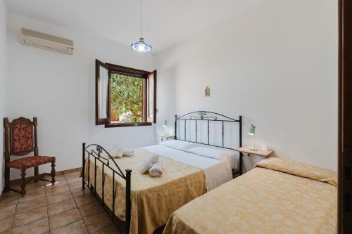 a bedroom with two beds and a chair and a window at Baglio Montoleone in Castelluzzo