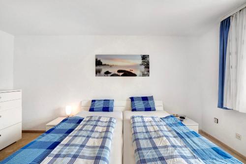 two beds in a white bedroom with blue pillows at Wohnung zum Hirschen in Gräfelfing