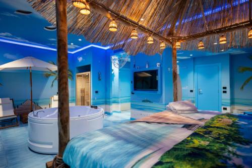 a bedroom with a tub and a bed with a straw roof at Hotel Art Village in Casoria