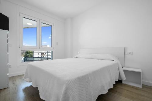 a white bedroom with a white bed and a window at Formentor 863 in Salou