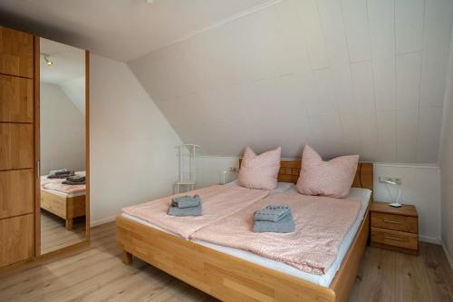 a bedroom with a bed with pink pillows and a mirror at 5 Sterne Ferienwohnung Boddenblick in Glowe