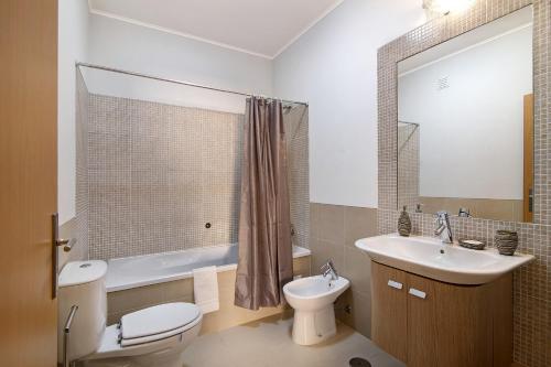 a bathroom with a toilet and a sink and a tub at Royal Cabanas Golf 85 in Cabanas de Tavira