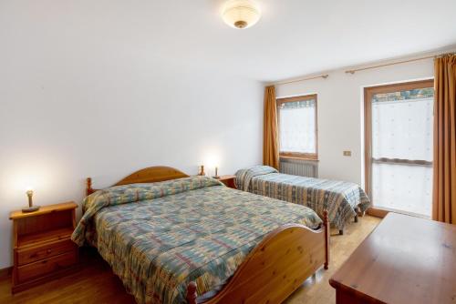 a bedroom with two beds and a table at Residence Malibu Appartamento 7 in Falcade