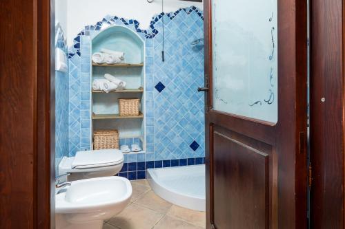a blue tiled bathroom with a toilet and a sink at Giojas125 Monolocale per 4 persone in Orosei