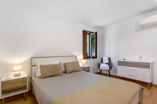 a white bedroom with a bed and a chair at Casa Do Pião - Turismo Rural in Ancião