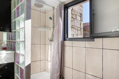 ein Badezimmer mit Dusche und Fenster in der Unterkunft Casaesquerda Cinza in Vieira do Minho