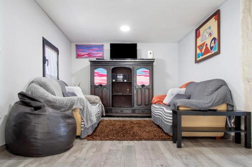 a living room with two chairs and a tv at Casaesquerda Cinza in Vieira do Minho