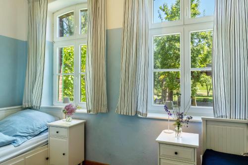 a bedroom with a bed and two windows at Der Flusshof, Ferienhaus in Werben