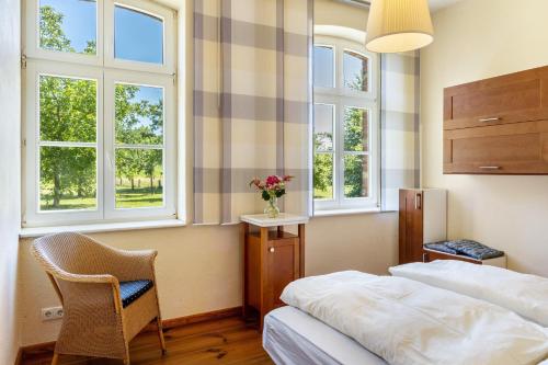 a bedroom with a bed and a chair and windows at Der Flusshof, Ferienhaus in Werben