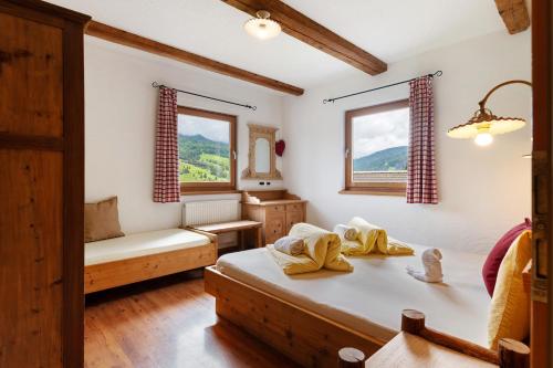 a bedroom with a bed and a couch and two windows at Paracia App La Vedla in Badia