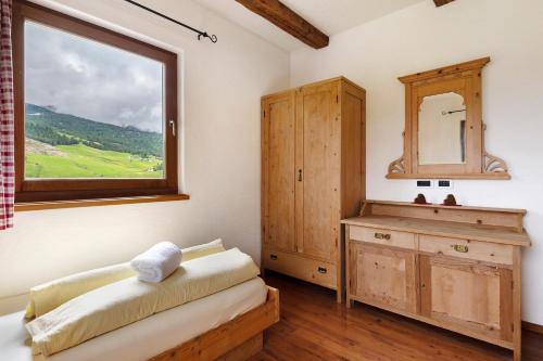 a bedroom with a window and a wooden dresser at Paracia App La Vedla in Badia