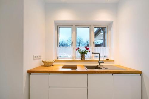 eine Küche mit Spüle und Fenster in der Unterkunft Lüttdeel in Gelting