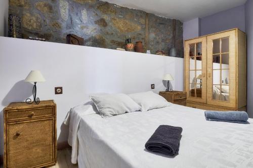 a bedroom with a white bed and a wooden cabinet at La Casa De Anta in Asturianos